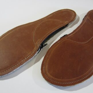 Unfilled custom leather orthotic showing empty arch pouch before millet hulls are added, with leather, wool, and hemp layers visible.