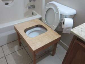 Wooden full squat toilet platform positioned over standard toilet bowl.