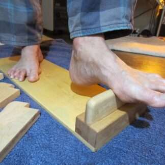 Wooden Foot Friend multi tool shown on floor for deep foot massage.