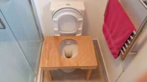 Wooden squatting toilet platform designed to promote healthy, natural posture during use.